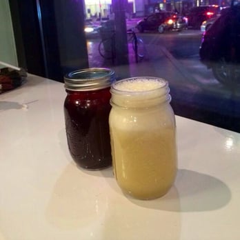 Two mason jars of juice and smoothie by the window at night